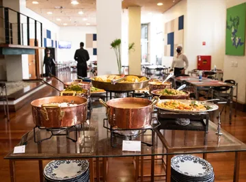 Panelas de variados tamanhos com comidas diversas estão em cima de uma mesa.