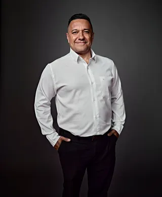 Anderson Luiz é um homem de pele morena e cabelo preto curto. Ele está usando uma camisa branca.