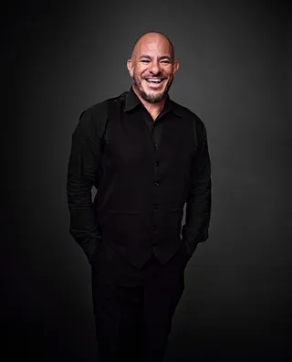 Fernando Coutinho is a white adult man who is bald. He is wearing a black shirt and smiling for the photo.