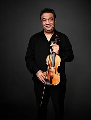 Florian Cristea is a white man with black hair. He is wearing a black shirt and holding a violin.