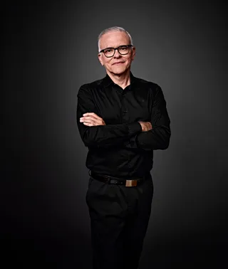 Ruben é um homem branco na casa dos 50 anos, com cabelo curto e grisalho. Ele está usando uma camisa preta e óculos.