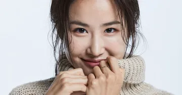 Hera Park é uma mulher asiática, de cabelos castanhos. Ela usa um vestido preto tomara que caia.