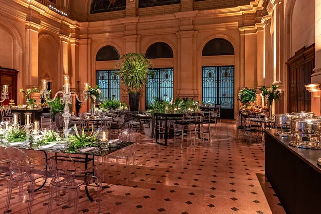 Vista do salão da Estação Motiva Cultural com mesas, cadeiras, plantas e iluminação para eventos