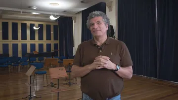 Foto de Giancarlo Guerrero. Homem branco, com cabelos medios e encaracolados.