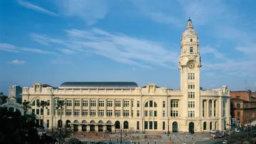 A foto colorida mostra o prédio da Sala São Paulo visto de cima em um dia ensolarado com céu azul.